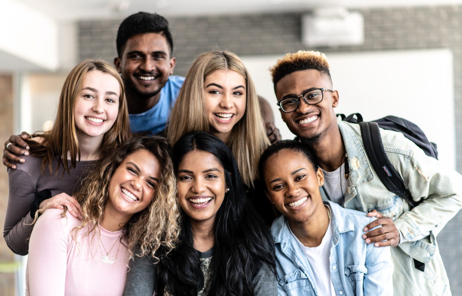 A diverse group of smiling young people standing close together, representing the range of workstyles a team brings to any room.