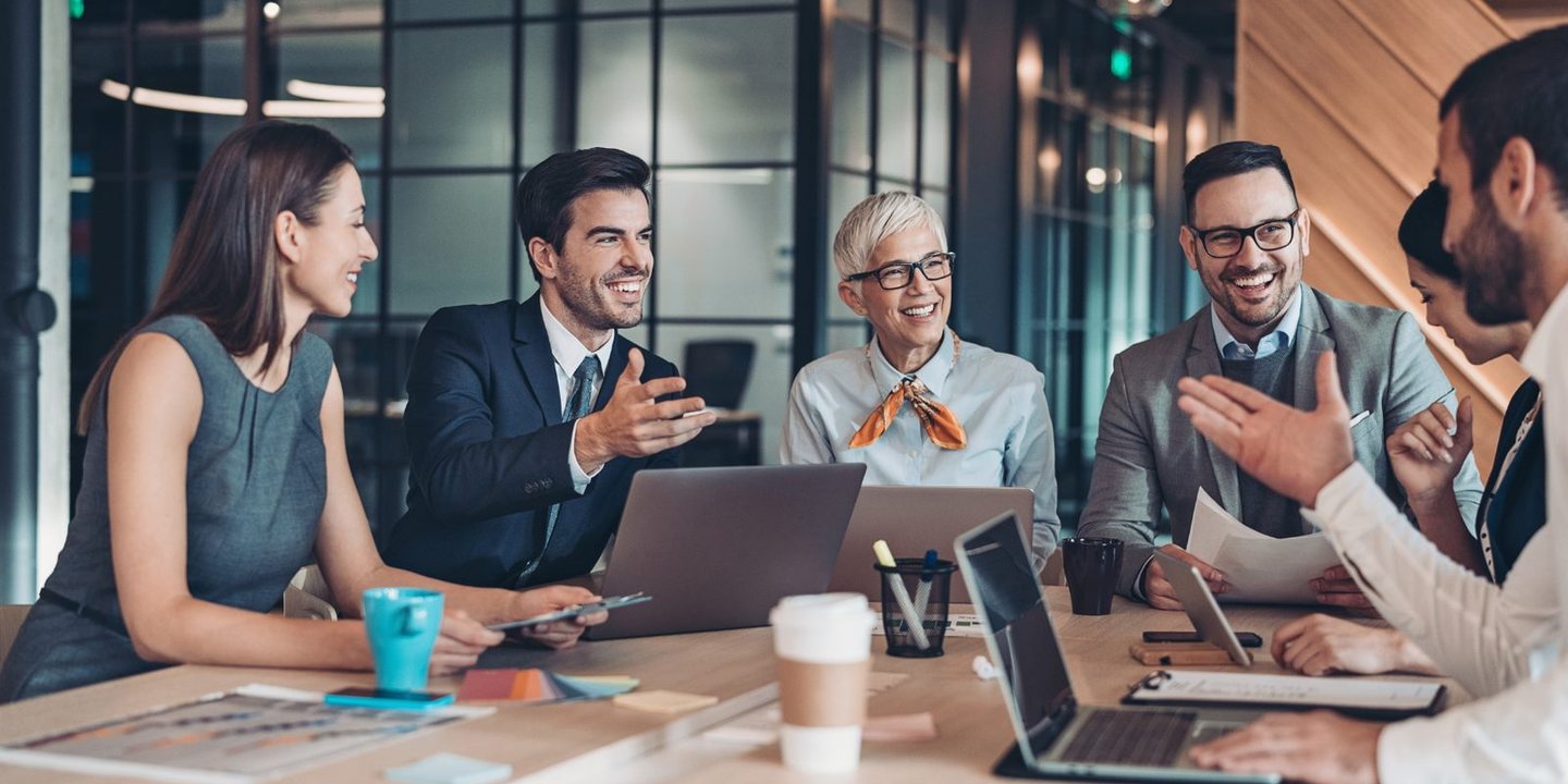 A leadership team in a relaxed, engaged conversation around a boardroom table